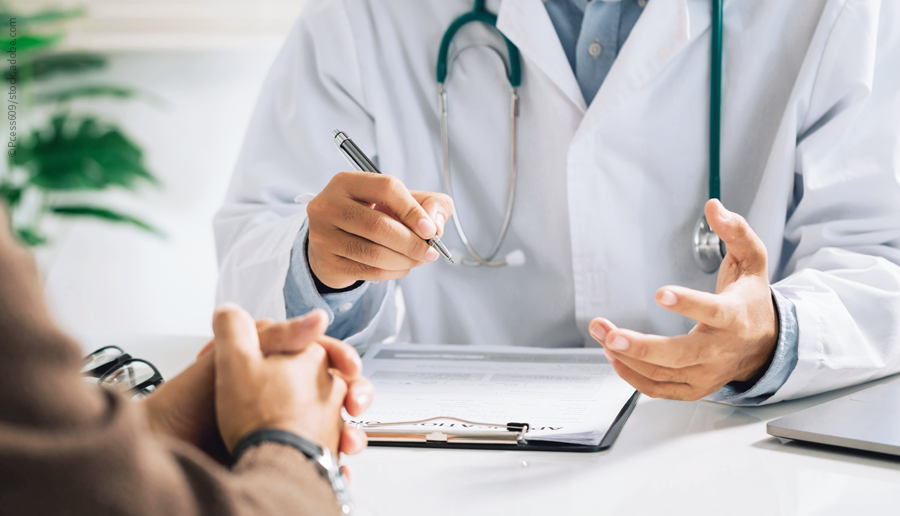 Foto mit Blick auf die Hände eines Arztes und eines Patienten in einer Gesprächssituation an einem Tisch